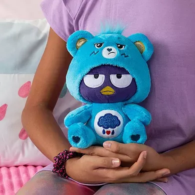 A person is holding a blue plush toy with a bear-like body and a grumpy bird face.