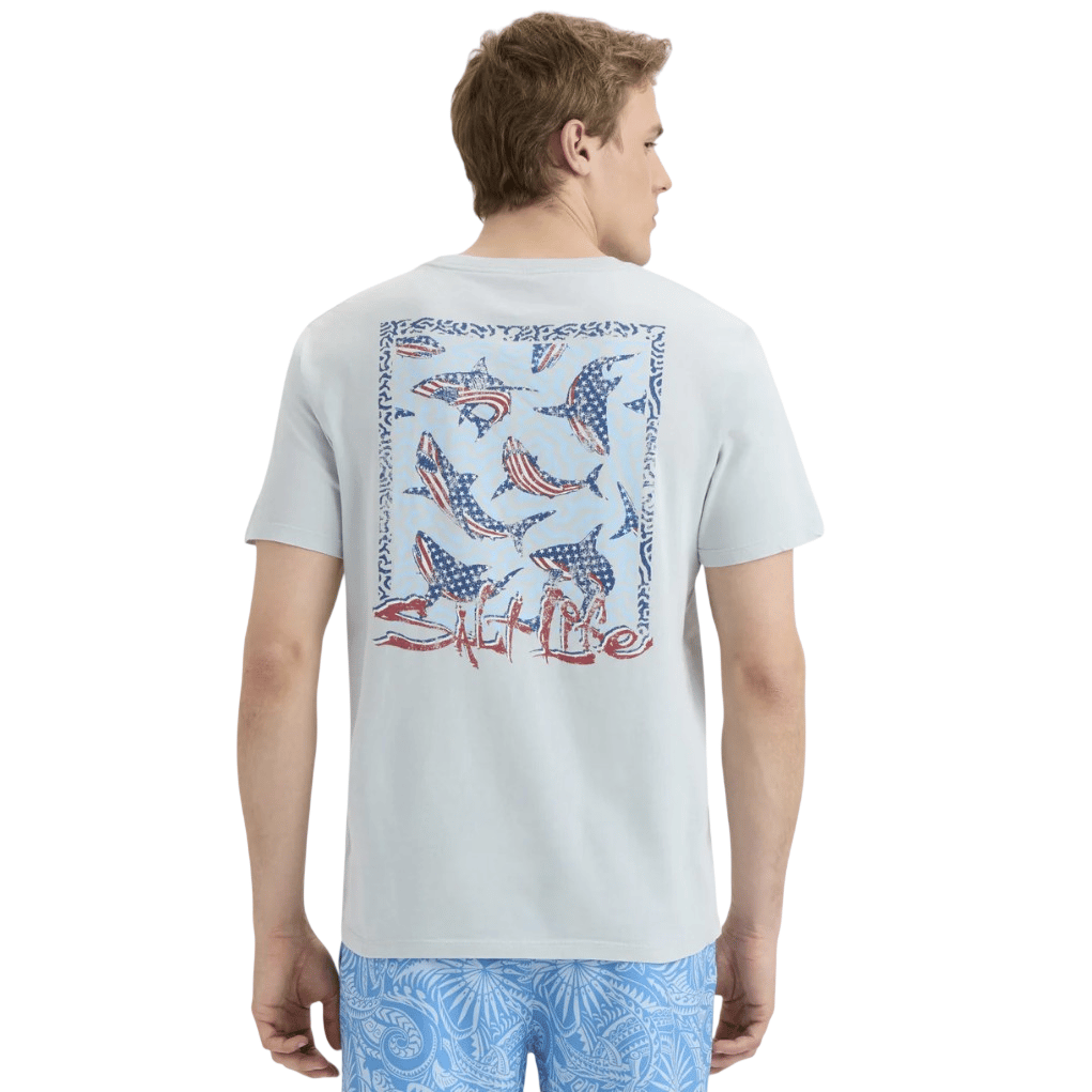 A man wearing a light-colored T-shirt with a graphic of fish and the text \“Salt Life\“ on the back, paired with blue patterned shorts.