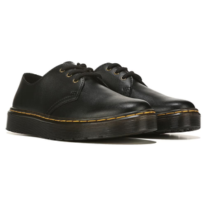 A pair of black leather lace-up shoes with a thick rubber sole accentuated by yellow stitching.