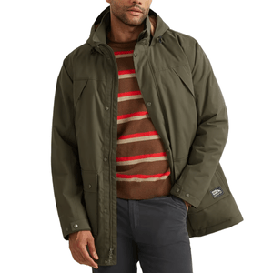 A man wears an olive-green hooded jacket over a brown sweater with red and beige stripes, paired with dark pants.
