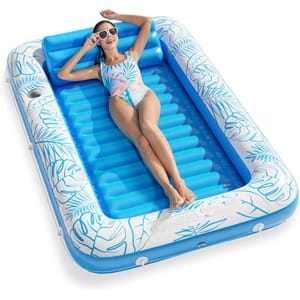An inflatable pool float with a blue and white tropical leaf design, featuring a reclining woman in a swimsuit and sunglasses.