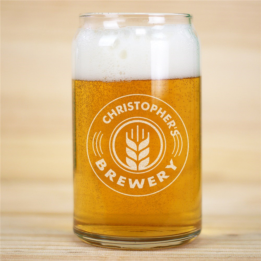 A glass shaped like a beer can filled with light amber beer, featuring the logo \“CHRISTOPHER'S BREWERY\“ and a wheat design in white.