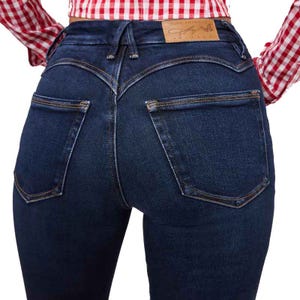 Dark blue denim jeans with contrasting stitching and back pockets, paired with a red and white checkered shirt.