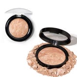 Two compact powders in black cases, one open and surrounded by loose powder. Both have a marbled, earthy-toned appearance with a clear lid.