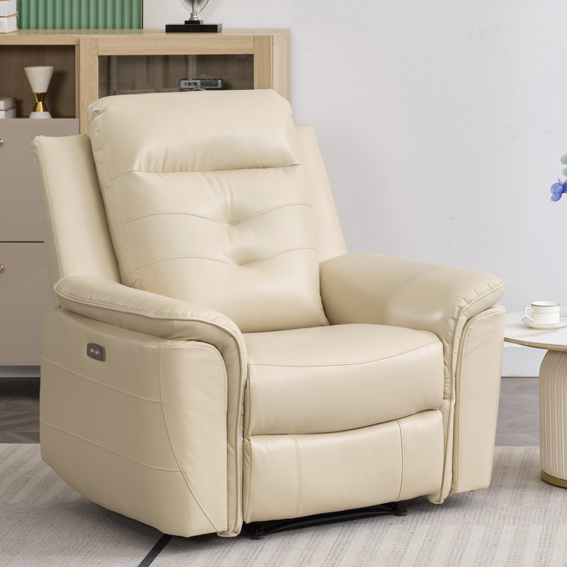 A beige recliner chair with a modern design featuring plush cushions and a built-in control panel sits in a living room setting next to a small round side table with a cup on it.
