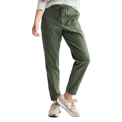 A person wearing olive green jogger pants paired with casual beige and white sneakers.