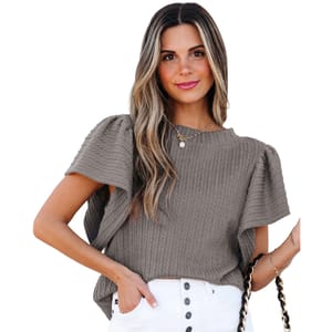 A woman wears a textured gray top with puff sleeves and white buttoned pants, accessorized with a gold necklace and a chain strap purse.