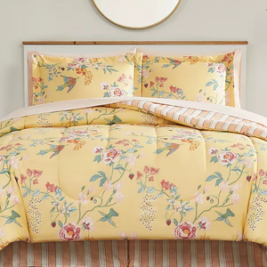The 8pc Spring Floral Comforter Set features a yellow comforter with a colorful floral pattern, matching shams, and a striped reverse side. The set includes coordinated sheets, creating a cohesive and inviting bedroom look.