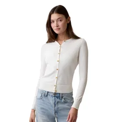 A woman is wearing a white button-up cardigan with long sleeves paired with light blue jeans.