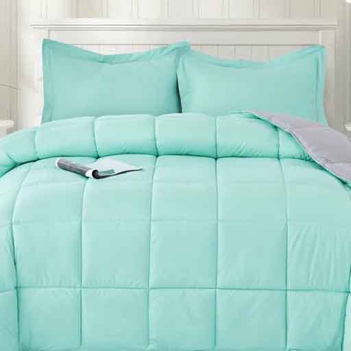 A light turquoise comforter set with two matching pillow shams on a bed, featuring a quilted design. A book is placed on the comforter.