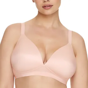 A woman is modeling a light pink, wireless bra featuring molded, smooth cups and adjustable straps.