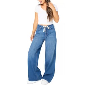 A woman is wearing high-waisted, wide-leg blue jeans with a white drawstring and a short-sleeved, white cropped top, paired with white sneakers.