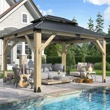 A wooden gazebo with a metal roof is set up on a patio beside a pool, featuring outdoor furniture, a guitar, and a small lantern.