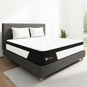 A modern bed with a white and black Avenco mattress, two white pillows, a dark gray upholstered frame, and a small plant beside.