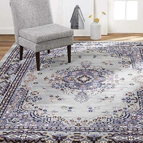 A traditional-style area rug featuring a central medallion pattern with floral motifs in shades of gray, blue, and beige, bordered by navy and tan accents.