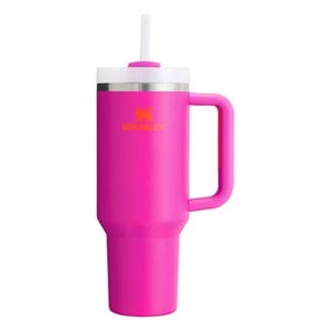 A bright pink Stanley insulated tumbler with a handle and a straw, featuring a stainless steel rim and a prominent logo.