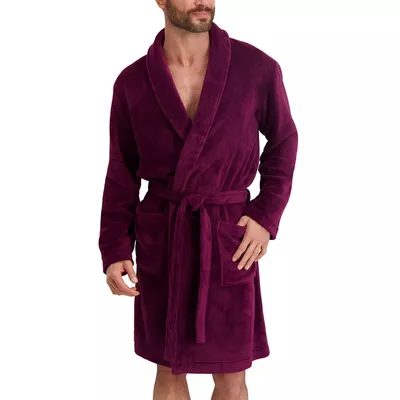 A man is wearing a plush, burgundy bathrobe with a shawl collar, waist tie, and two front pockets.