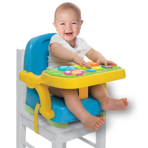 A baby sits in a bright blue booster seat with a yellow activity tray, featuring colorful buttons and dials, placed on a white chair. Ideal for keeping infants entertained and secure during feeding or playtime.