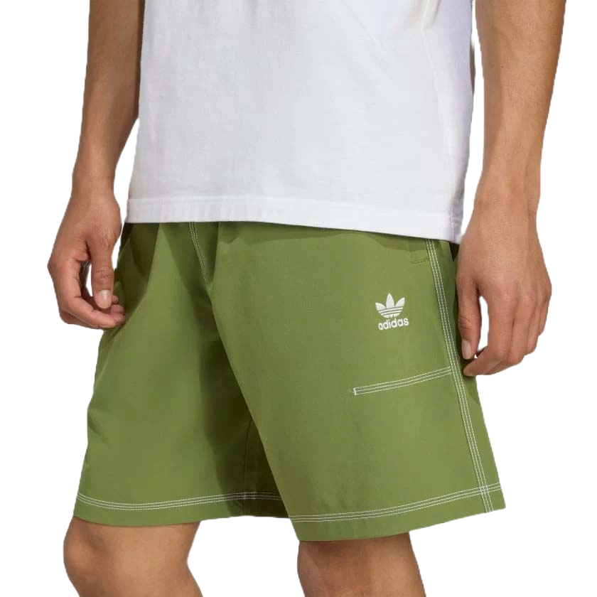 A person wearing olive green Adidas shorts featuring white stitching and the Adidas logo on the side, paired with a white T-shirt.