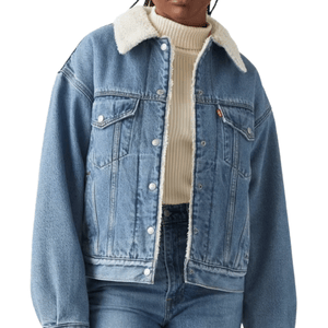 A blue denim jacket with a white shearling collar, button-up front, and front pockets, worn over a cream ribbed turtleneck sweater.