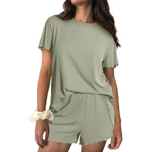 A woman wearing a light green, short-sleeve, ribbed lounge set with matching shorts. She has a light-colored scrunchie on her wrist.