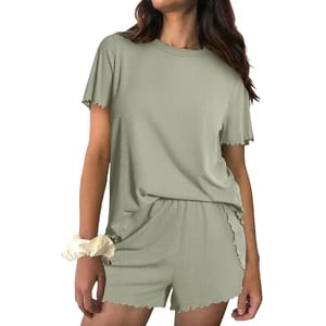 A woman wearing a light green, short-sleeve, ribbed lounge set with matching shorts. She has a light-colored scrunchie on her wrist.