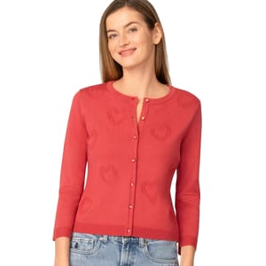 Red cardigan sweater with heart patterns, featuring a button-up design and three-quarter sleeves, paired with blue jeans.
