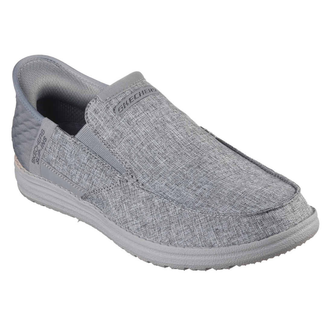 Gray slip-on shoe with a textured fabric design, labeled \“Skechers\“ on the top and sides.