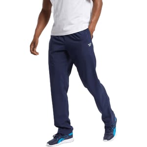 Reebok Woven Training Pants are lightweight, navy blue pants designed for athletic activities, featuring a relaxed fit with an elastic waistband and the Reebok logo on the side.