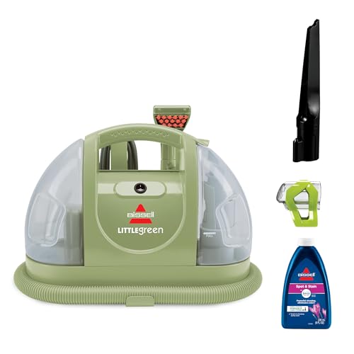 A compact green and translucent Bissell Little Green Carpet Cleaner with an attached hose, a spray nozzle, a crevice tool, and a bottle of cleaning solution.