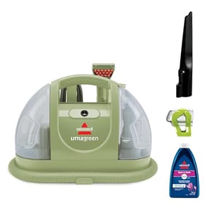 A compact green and translucent Bissell Little Green Carpet Cleaner with an attached hose, a spray nozzle, a crevice tool, and a bottle of cleaning solution.