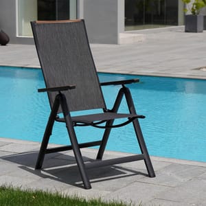 A black outdoor lounge chair with a fabric backrest and seat, beside a swimming pool.