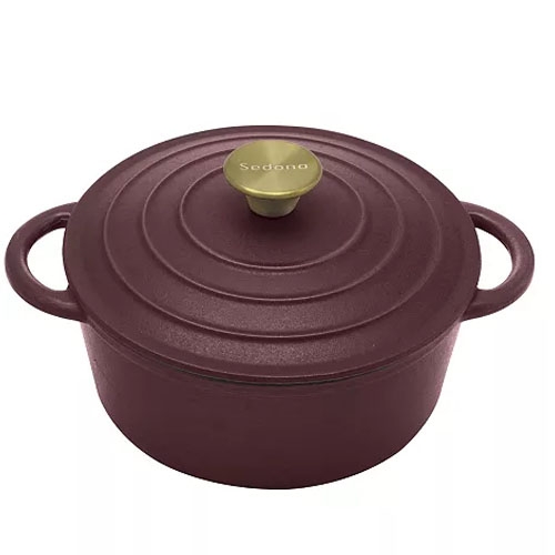 A maroon cast iron Dutch oven with a lid, featuring dual handles and a brass knob labeled \“Sedona.\“