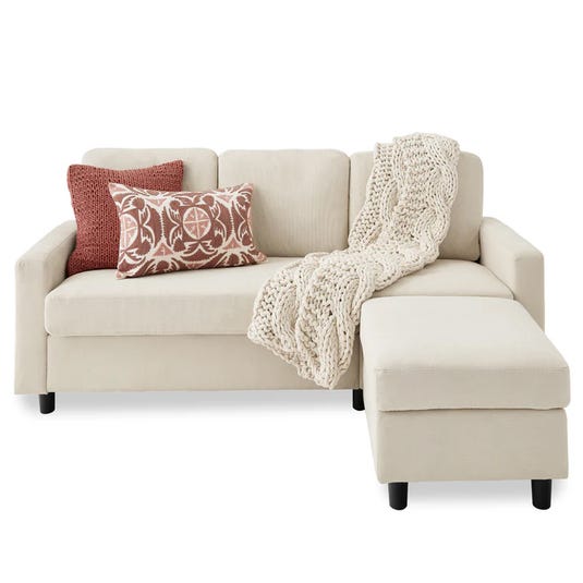 A beige sectional sofa with an attached chaise, accented by a knit throw blanket and decorative cushions.