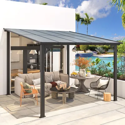 A modern outdoor patio with a metal-framed canopy, featuring seating including a sofa with pillows, a wicker chair, and a wooden armchair, surrounding a stone coffee table. A side table holds decorative vases, and a pool is visible in the background.