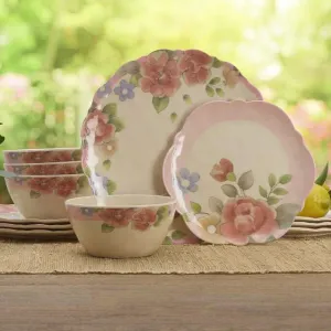A set of floral-patterned dinnerware featuring plates and bowls with pink and blue flowers and green leaves, displayed outdoors on a wooden table.