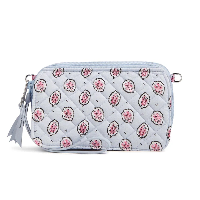 A quilted clutch with a blue background features a pattern of cute pink hedgehogs. It includes a zipper closure and a wrist strap.
