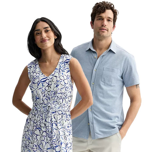 A woman in a sleeveless, floral-patterned, V-neck dress stands beside a man wearing a short-sleeve, light blue button-up shirt paired with light-colored pants.
