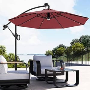 A red outdoor cantilever umbrella providing shade over a patio set with two chairs and a table.