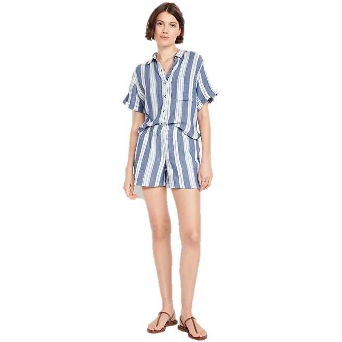 A woman is wearing a blue and white vertically striped shirt and matching shorts set, paired with brown sandals.