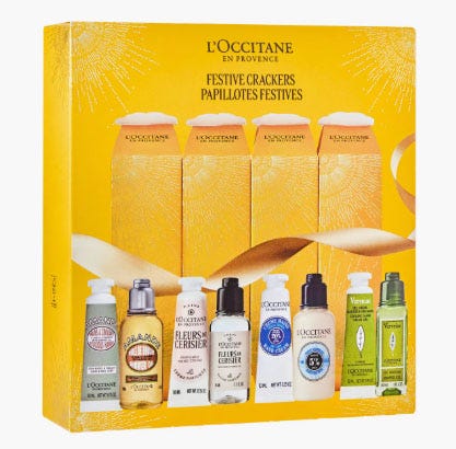 L'Occitane Festive Crackers set includes six body care products: shea butter hand cream, almond shower oil, cherry blossom hand cream, lavender foaming bath, essential oil shampoo, and verbena body lotion.