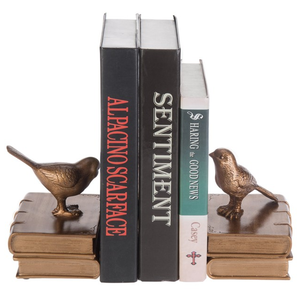 Gold bird bookends support three books: \“Al Pacino Scarface,\“ \“Sentiment,\“ and \“Sharing the Good News\“ by Casey.
