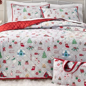 A festive bedding set featuring Christmas-themed designs with trees, stockings, and holiday phrases like \“Joyeux Noel\“ and \“Merry Christmas,\“ in red, green, and white colors. The set includes a quilt, pillowcases, and a matching bag.
