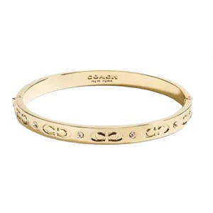 Gold-toned Coach Outlet hinged bracelet featuring embossed double \“C\“ logos and small circular embellishments. It has a sleek and minimalist design.