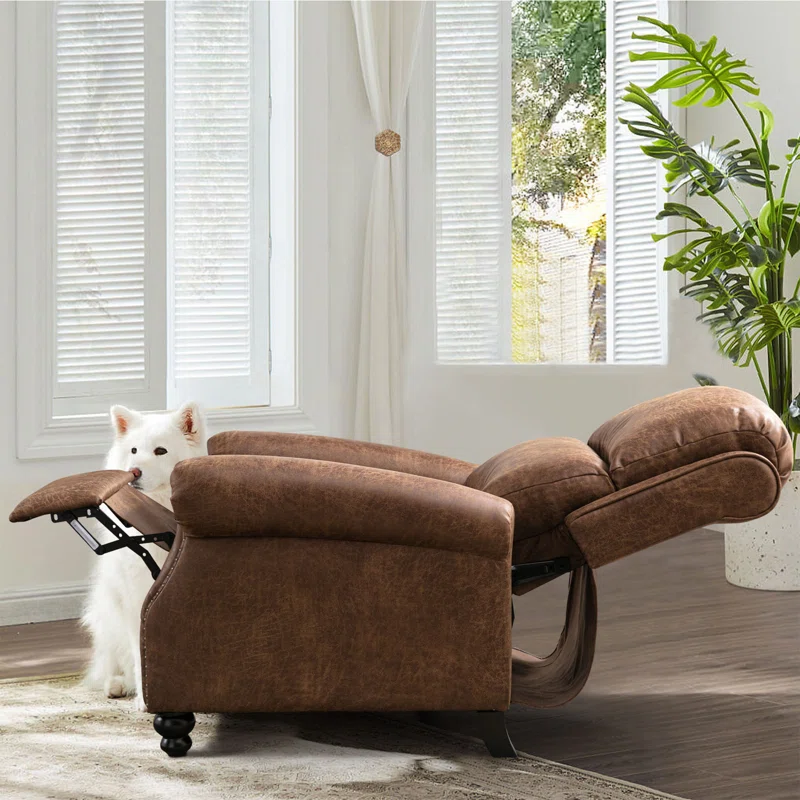 A brown chaise lounge and a white dog peeking from behind it in a room with white curtains and a potted plant.