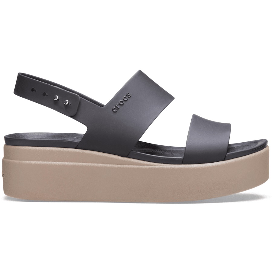 The Crocs Brooklyn Wedge Low Sandals feature a black, two-strap design with an adjustable ankle strap on a beige platform sole, offering style and comfort.