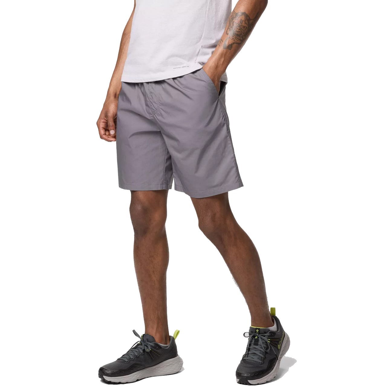 A person is wearing gray shorts paired with black running shoes featuring lime green accents.