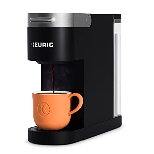 A compact single-serve Keurig K-Slim Coffee Maker with a black body and a clear water reservoir on the side, dispensing coffee into an orange mug.