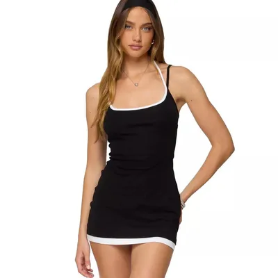 A woman wearing a form-fitting black mini dress with white trim on the straps and hem, and a matching headband.
