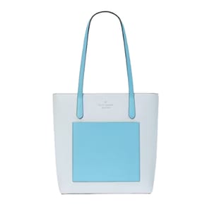 A two-tone Kate Spade tote bag with a large blue square on the front, blue handles, and the brand name at the top center.